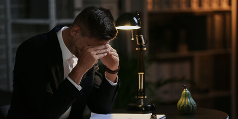 Depressed young businessman in office late in evening