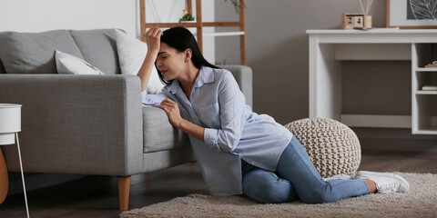 Depressed young woman sitting on floor at home