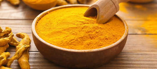 Bowl with aromatic turmeric and scoop on wooden background, closeup