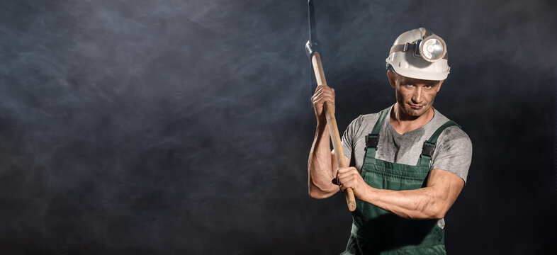 Miner man with pick axe on dark background with space for text