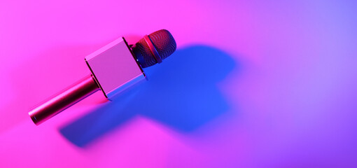 Modern microphone on bright color background, top view