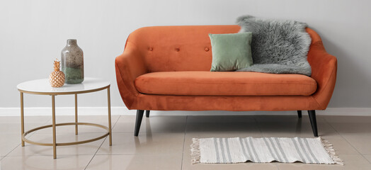 Stylish sofa and table near light wall