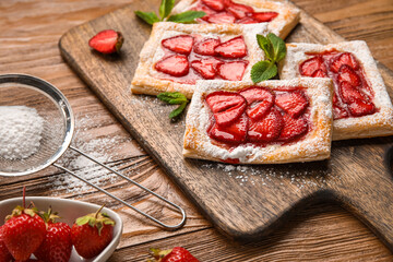 Delicious strawberry puff pastry and sieve with sugar powder on wooden table, closeup