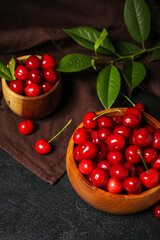 Wooden bowls with sweet cherries on dark background