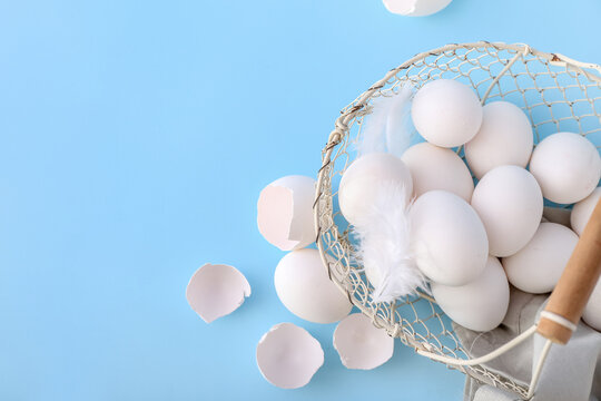 Basket with white chicken eggs on color background