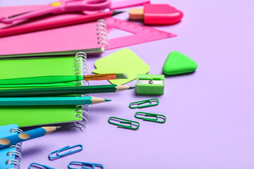 Colorful school stationery on lilac background, closeup