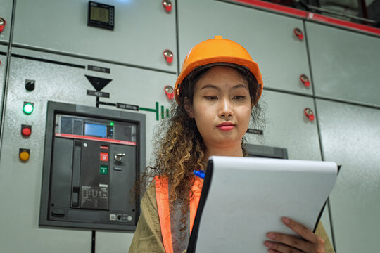 worker in a helmet. Engineer checking and monitoring the electrical system in the control room. Worker checking and inspecting at switchgear panel.