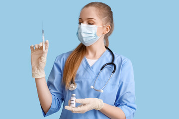 Female doctor with monkeypox vaccine and syringe on blue background
