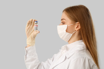 Female doctor with monkeypox vaccine on light background