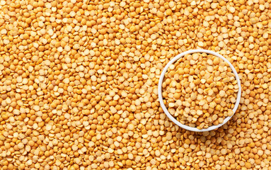 ceramic plate with dried peas on a yellow peas background close-up top view.