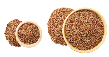 Grains buckwheat are scattered out of the wooden bowl top view.