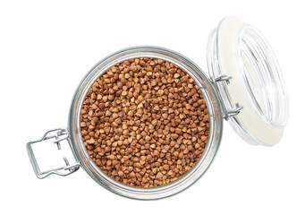 Heap of uncooked dry buckwheat grains in glass storage jar isolated on white background top view.