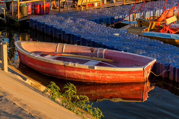 Fototapeta na wymiar Wooden red boat at the pier. Rowing boat on the Chagan River