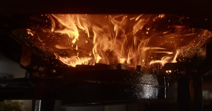 Very close bottom view of a lit camp stove where a pan is placed which creates a fireball, 4k DCI, 240fps, super slow motion, super closeup