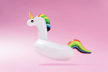 Creative art minimal aesthetic. Inflatable unicorn pool toy on pastel pink background. Minimal...