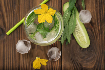Cucumber and peppermint slices in a glass on a wooden table on a blue background. Flat lay.