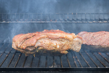 This is a typical American food with grilled beef steaks and pork ribs on a hot BBQ grill