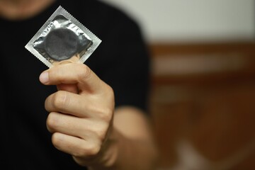Ready-to-use condoms in male hand ,
concept on the bed Prevent infection.