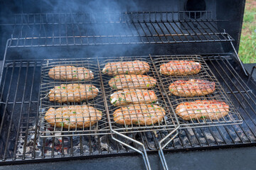 On the hot BBQ grill, mixed American barbecue food is grilled on burgers beef roasts