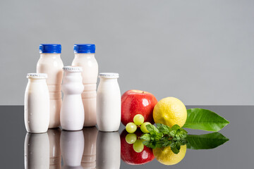 Dairy products containing probiotics, bifidobacteria and vitamins. White bottles with yogurt, fruits and greens probiotic food concept. Bifidobacteria increase immunity. Probiotics improve digestion.