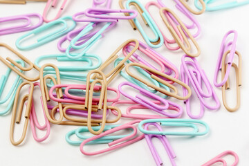 Multicolored paper clips scattered as textured background in full screen. Stationery concept.
