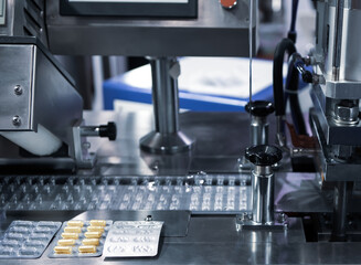 Capsule blister packing machine in pharmaceutical industry. - obrazy, fototapety, plakaty