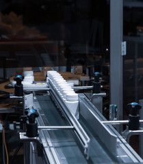White plastic bottle on capsule filling machine conveyor belt in production line. Pharmaceutical...