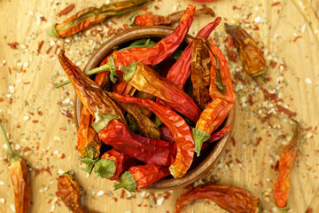 Chili peppers falling, spice seasoning, dried red peppers on a wooden table, background, dry paprika. Selective focus