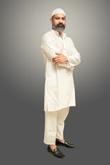 Portrait of asian indian muslim man standing with cross arms isolated over grey background.