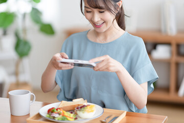 Obraz na płótnie Canvas 朝食の写真を撮る女性