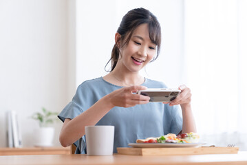 Obraz na płótnie Canvas 朝食の写真を撮る女性