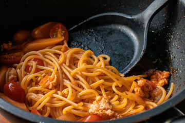 Spaghetti with tomato sauce, chicken and sausage in black plate top view. Flat lay.