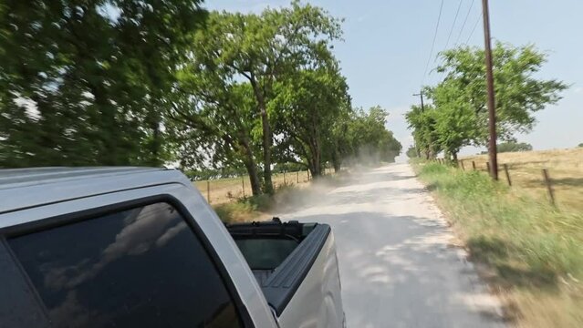 Pickup truck driving down a dusty dirt road in the rural Texas farmland