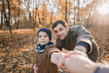 boy with dad in autumn forest with orange leaves