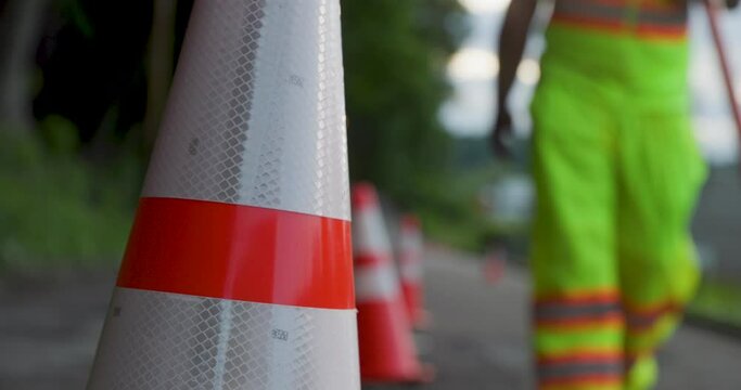 Road Construction Flagger Walking with Stop / Slow Sign Past Traffic Cones