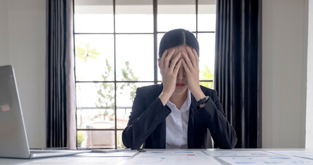 Young Asian businesswoman working on a tablet, is stressed has a headache and thinks hard at the office.