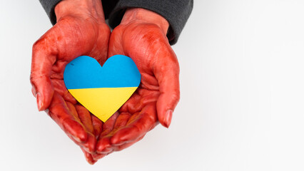 Woman with hands covered in blood holding a heart with the flag of ukraine on a white background. 