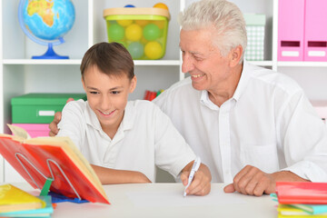 Grandfather with grandson doing homework at home