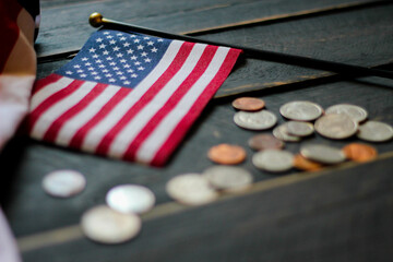 Flag of the United States on coin on black wooden floor.