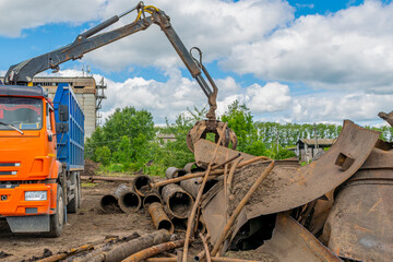 Hydraulic arm of grapple manipulator grabs scrap metal for loading into special transport vehicle. - obrazy, fototapety, plakaty