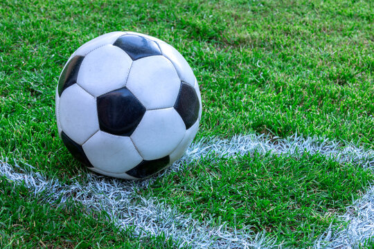 A soccer field with a football on a corner. A football is a ball inflated with air that is used to play one of the various sports known as football.
