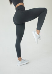 A big woman booty in leggings on grey background.