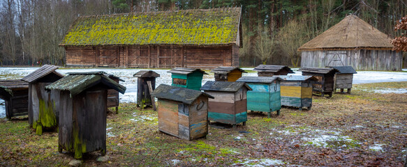 Old hives on display in the open-air museum of folk culture. The photo was taken on a cloudy winter...