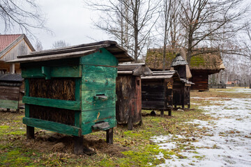 Old hives on display in the open-air museum of folk culture. The photo was taken on a cloudy winter day.