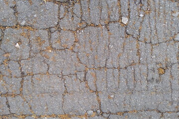 Photo of an asphalt road in cracks. Cracks on the paved road. Rough abstract urban background.
