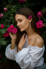 beautiful brunette girl in the garden with pink roses flowers