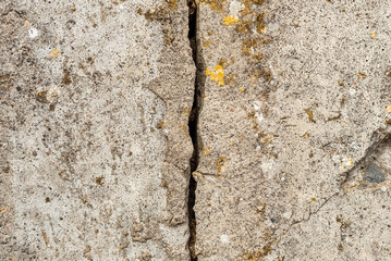 Large crack running vertical through a cement wall.Cracked stone wall background.black,gray cracked floor texture.Closeup.
