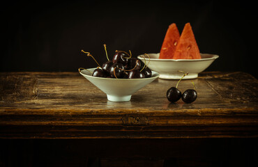 Still life of Chinese white antique ceramics with group of cherry and slides of watermelon against...