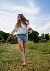 free slim brunette woman walking on the meadow opposite blue sky