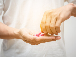 Close up man hand pour pills out of medicine bottle